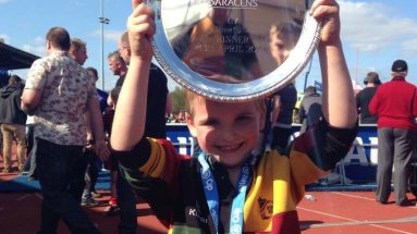 Young rugby player celebrates winning by holding trophy above his head