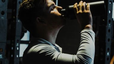 Personal trainer drinking from a water bottle promoting hydration for young athletes