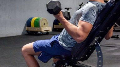 Young male performing arm curls strength training with youth fitness coach Ascot