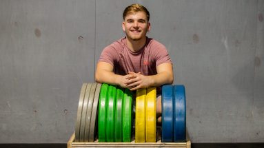 Male personal trainer posing next to weightlifting equipment. Helping young people from the hidden health hazards of gaming